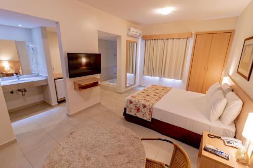 a hotel room with a bed and a television and a bathroom at Hotsprings Suite Hotel in Caldas Novas