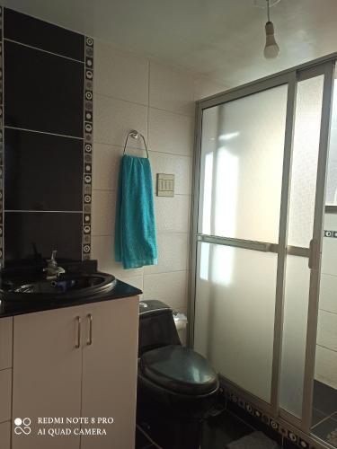 a bathroom with a toilet and a blue towel on the wall at DEPARTAMENTO JOSE MARIA in Achumani