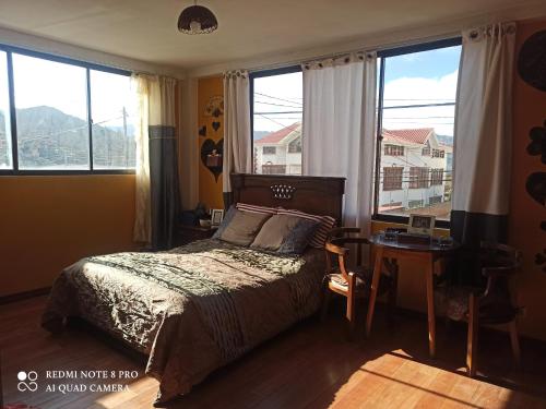 a bedroom with a bed and a table and windows at DEPARTAMENTO JOSE MARIA in Achumani