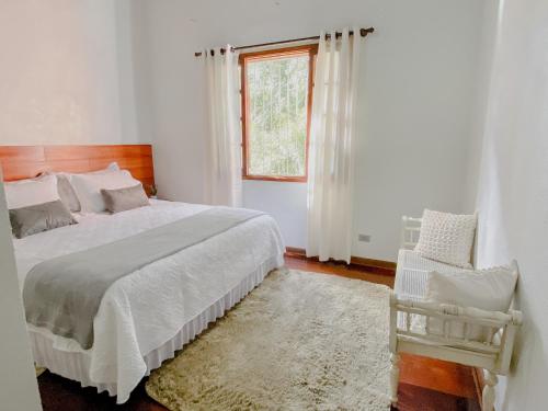 a bedroom with a bed and a window and a chair at Casa de Campo Vizinha da Lua in Monte Verde