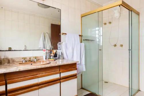 uma casa de banho com um lavatório e uma cabina de duche em vidro. em Suítes encantadoras em São Paulo