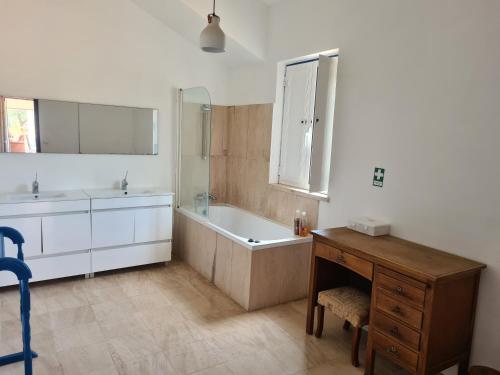 een badkamer met een bad, een wastafel en een bureau bij MONTE DOS FALEIROS in Ermidas