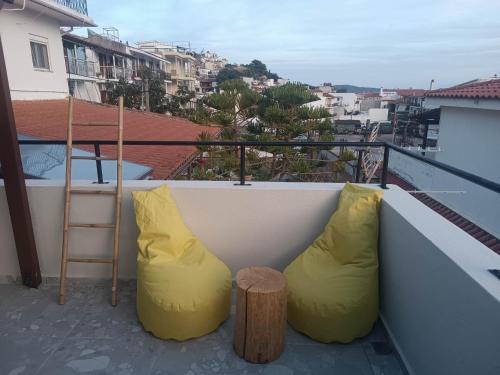 a balcony with two yellow pillows and a table and a view at Grecos STAY SKIATHOS in Skiathos Town