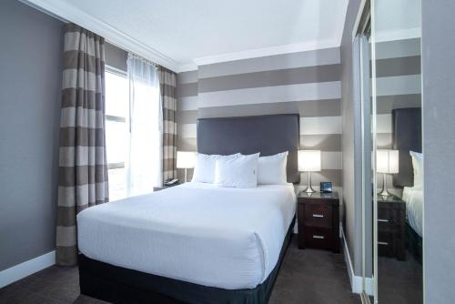a bedroom with a white bed and a large window at Sandman Signature Mississauga Hotel in Mississauga