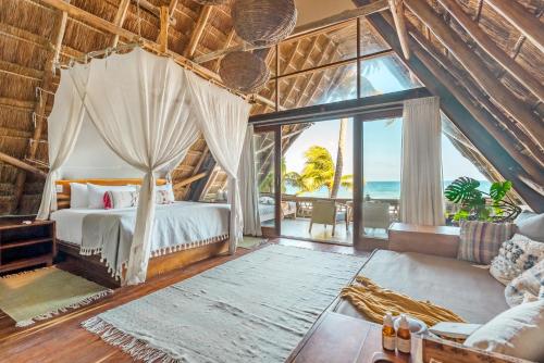 a bedroom with a bed with a view of the ocean at Ahau Beachfront Tulum Hotel in Tulum