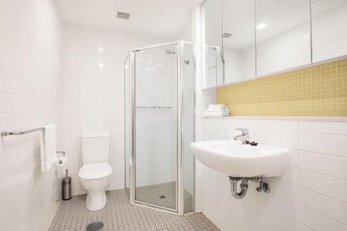 Baño blanco con aseo y lavamanos en Coast on Colley Luxury 1BR Glenelg, en Glenelg