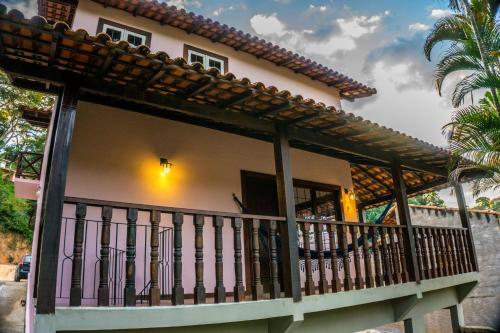 a house with a balcony and a palm tree at Casa Rosada seu refúgio na serra in Miguel Pereira