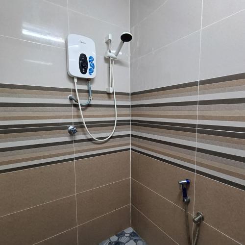 a shower in a bathroom with brown and white stripes at Kota Lodge Guest House in Melaka