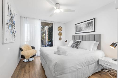 a white bedroom with a bed and a chair at Kirra Views in Gold Coast