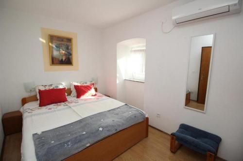 a bedroom with a bed with red pillows and a mirror at Apartments by the sea Punat, Krk - 21299 in Punat