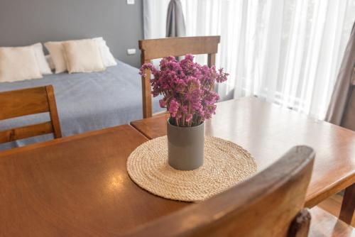 a vase of purple flowers sitting on a wooden table at Hotel Faro Azul Valparaíso Cerro Alegre in Valparaíso