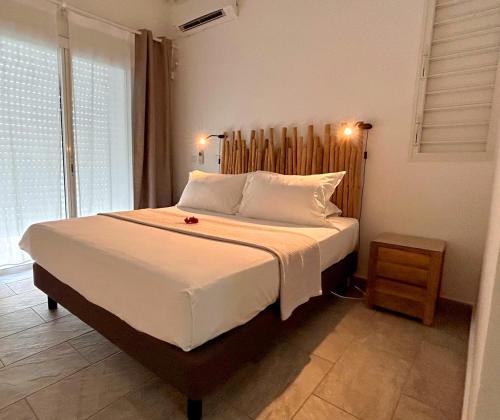 - une chambre avec un grand lit et une tête de lit en bois dans l'établissement Villa Sinoé, à Petit-Bourg