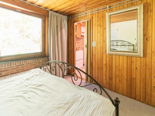 1 dormitorio con cama, ventana y espejo en Lovely chalet in Arendonk with terrace en Arendonk