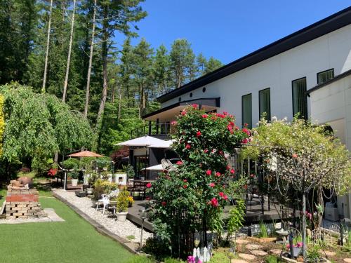 a building with a garden with red roses at Kakureyado Fujikawaguchiko in Fujikawaguchiko