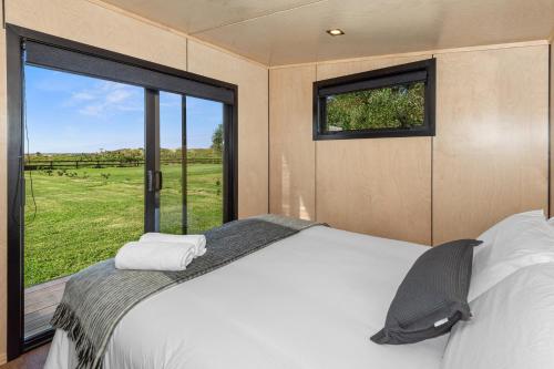 a bedroom with a bed and a large window at Peace in Paradise - Tokerau Beach Holiday Home in Tokerau Beach