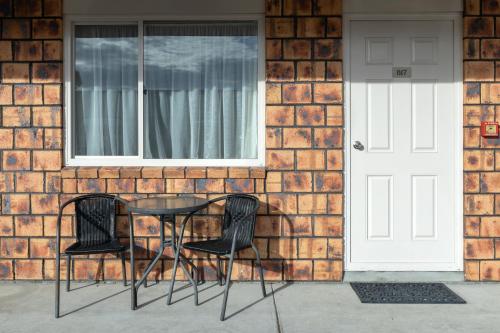 a table and chairs in front of a brick house at BK's Chardonnay Motor Lodge in Masterton