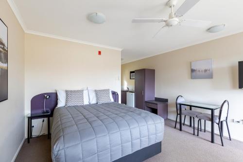 1 dormitorio con 1 cama y 1 mesa en BK's Chardonnay Motor Lodge en Masterton