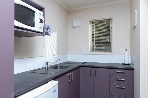 uma cozinha com um lavatório e um micro-ondas em BK's Chardonnay Motor Lodge em Masterton