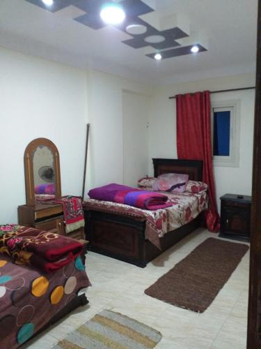 a bedroom with two beds and a mirror at شقة فندقية - رؤية واضحة للبحر - ابوقير - الاسكندرية in Abū Qīr