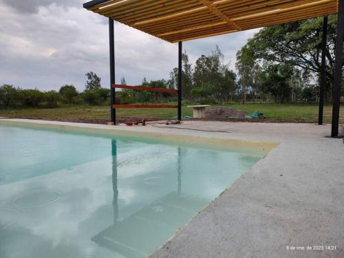 a pool of blue water with a gazebo at Quinta El Descanso in General Alvarado
