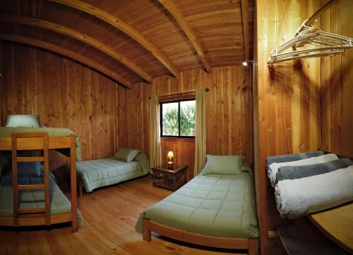 a room with two beds in a wooden cabin at Casa Vacacional Panguipulli in Panguipulli