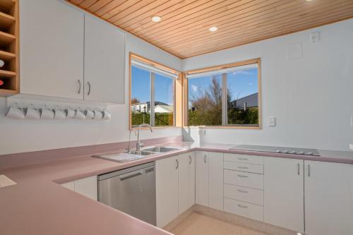 a kitchen with white cabinets and a wooden ceiling at Wanaka Tranquility - Wanaka Holiday Home in Wanaka