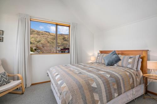 a bedroom with a bed and a large window at Wanaka Tranquility - Wanaka Holiday Home in Wanaka