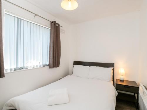 1 dormitorio con cama blanca y ventana en Sea Breeze, en Burnham-on-Sea