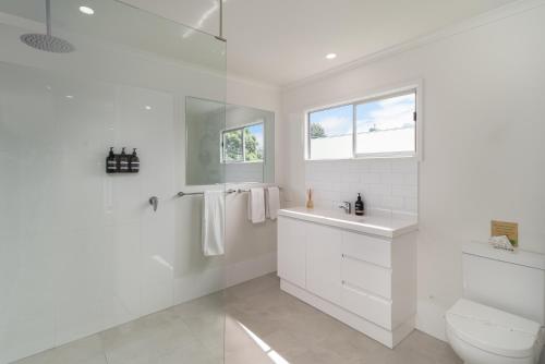 a white bathroom with a toilet and a sink at Little Bank House in Mount Tamborine