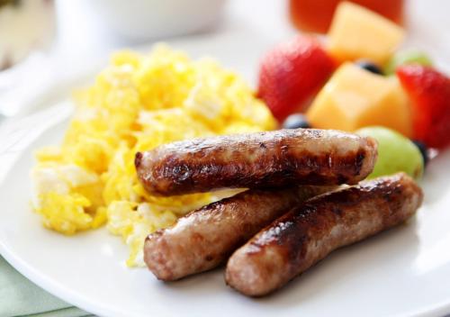 a plate of breakfast food with sausage and scrambled eggs at Sudima Hotel Lake Rotorua in Rotorua