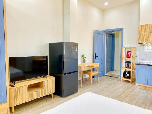 a living room with a large television and a kitchen at Moc Son Apartment - Attractive price for week and month stay - Serene Beachside Retreat Near Marble Mountains in Da Nang