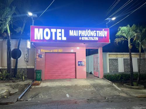 a motel with a red garage door and a neon sign at Mai Phương Thúy Motel in Bien Hoa