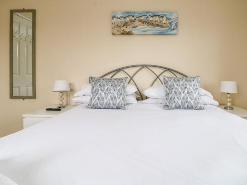 a bedroom with a white bed with blue pillows at Pentewan in Hayle