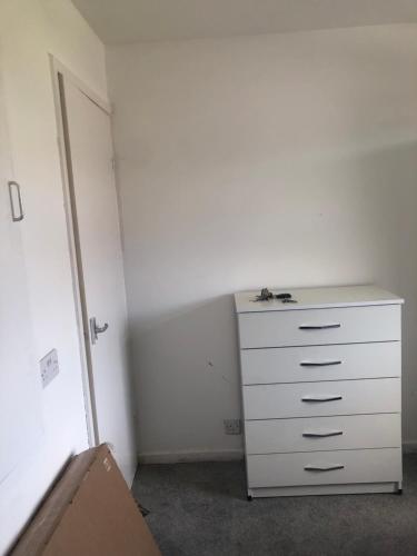 a white dresser in a room with a white wall at Falcon drive Room 2 in Oldham