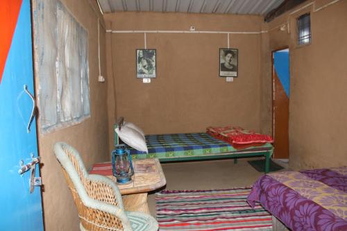 ランズドーンにある11 Gaon Mudhouse Homestayのベッド、テーブル、椅子が備わる客室です。