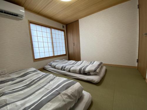 três camas num quarto com uma janela em WuTong梧桐 通天閣徒歩1分 NEW OPEN 景区内民宿 em Osaka
