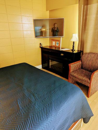 a bedroom with a bed and a piano and a chair at Above Tide Motel in Campbell River
