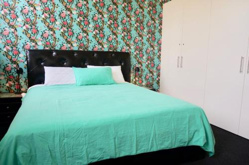 um quarto com uma cama com um edredão verde em Ozone Tower em Queenscliff