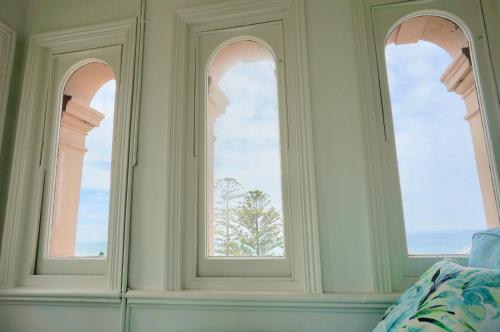 three arched windows in a bedroom with a tree at Ozone Tower in Queenscliff