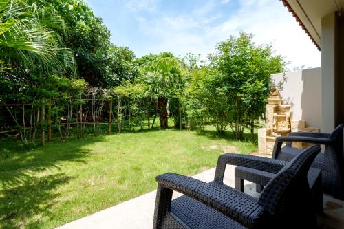 a porch with two benches and a yard with trees at GRANDVRIORESORT ISHIGAKIJIMA Ocean's Wing & Villa Garden in Ishigaki Island