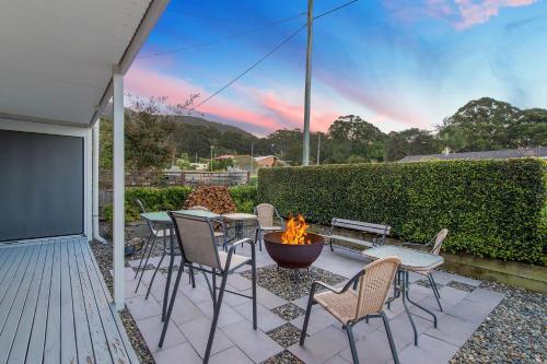a patio with tables and chairs and a fire pit at Castaway in Laurieton