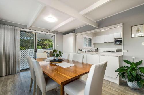 a kitchen and dining room with a wooden table and chairs at Castaway in Laurieton
