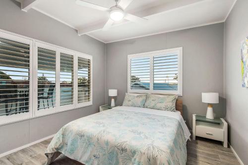 a bedroom with a bed and two windows at Castaway in Laurieton