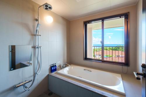 a bathroom with a bath tub and a window at GRANDVRIORESORT ISHIGAKIJIMA Ocean's Wing & Villa Garden in Ishigaki Island
