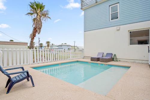 a swimming pool with two chairs and a house at 7 Heaven in Port Aransas
