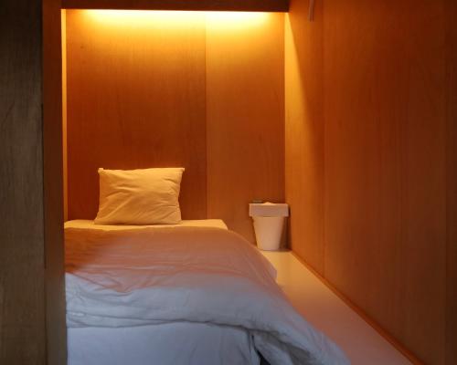 a small bedroom with a bed with a light on it at hostel mog in Ueda