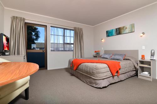 a bedroom with a bed with an orange blanket at Knightsbridge Court Motor Lodge in Blenheim