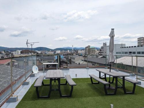 a patio with picnic tables and an umbrella on a roof at Guest House Kyoto Inn in Kyoto
