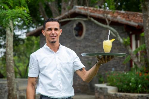 a man holding a plate with a drink on it at El Guayacán in Valle la Laguna