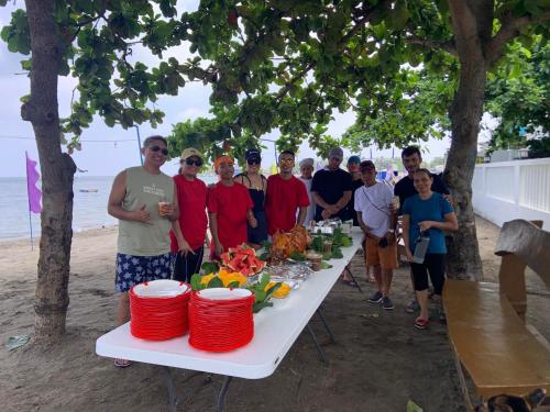BalibagoにあるBaie Benie Beach Resortの浜辺のテーブルの周りに立つ人々